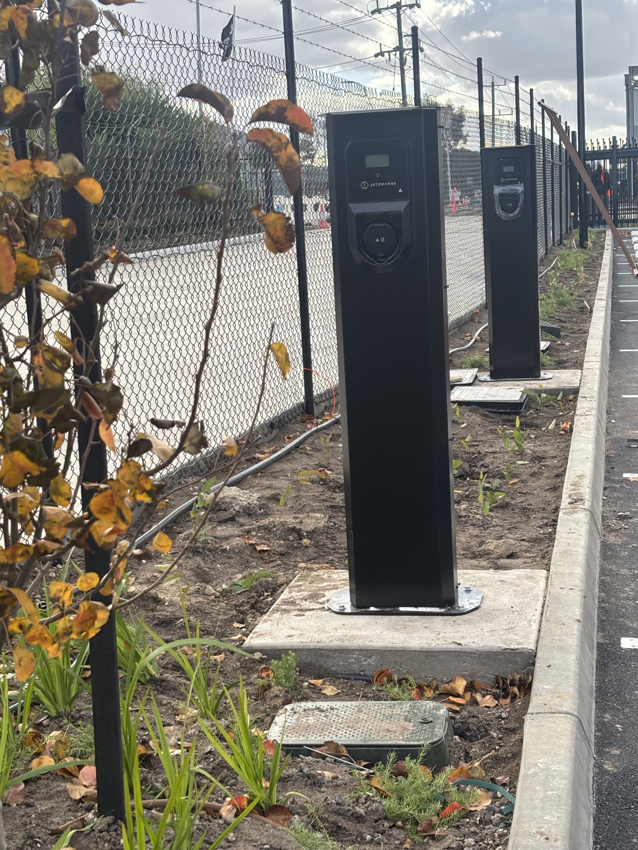 Row of black bollard lights installed along a fence line outdoors